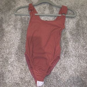 Rust color bodysuit with silver rings on straps